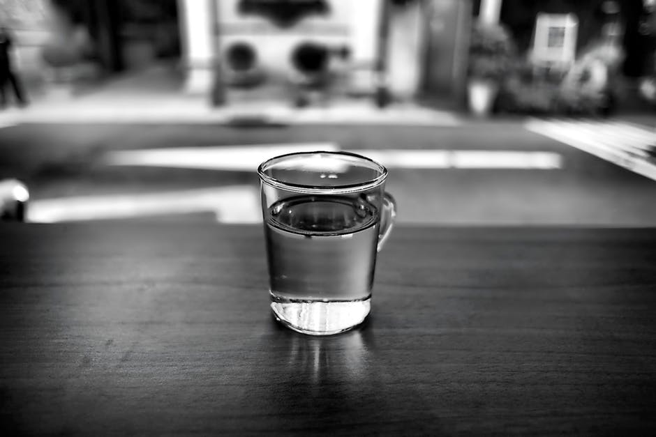 black and white photo of glass with water in it on a table