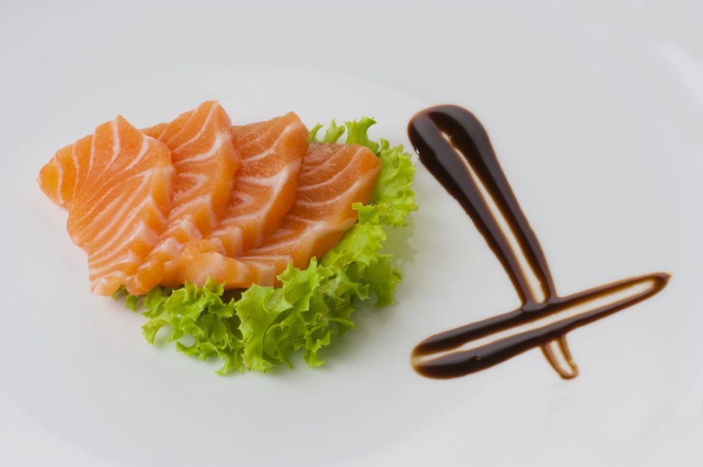 salmon sashimi with soy sauce on white background