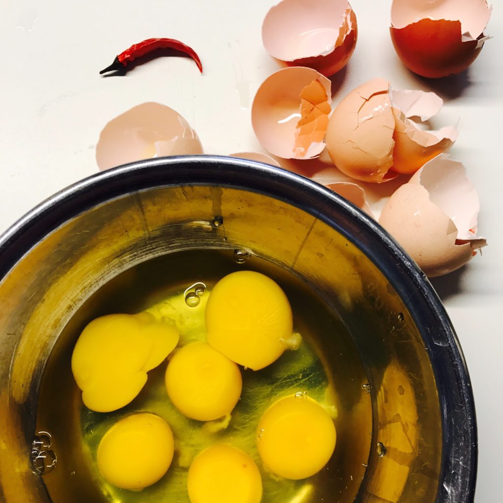eggs yolks in bowl with broken shells