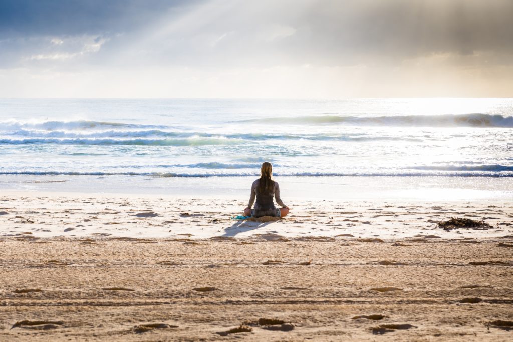female mediating on the beach at the ocean