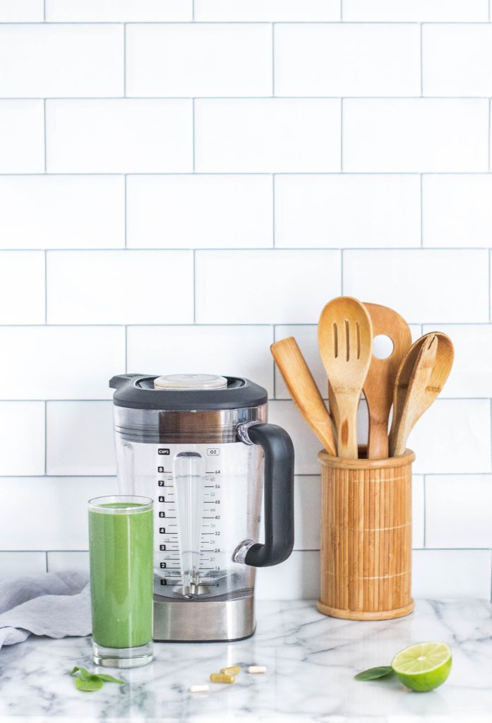 kitchen counter with blender, smoothie and utensils