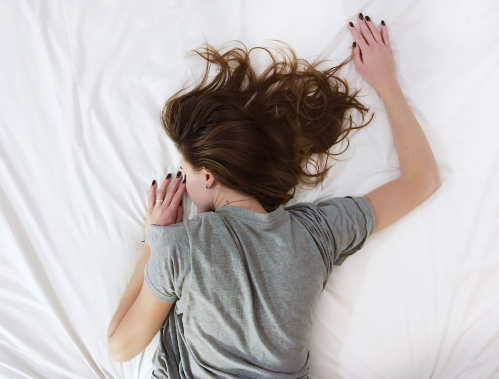 girl laying face down on white sheets
