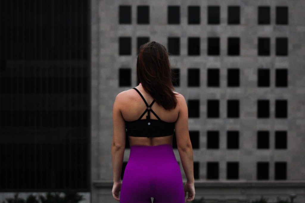 back of a lady in black workout bra and purple pants