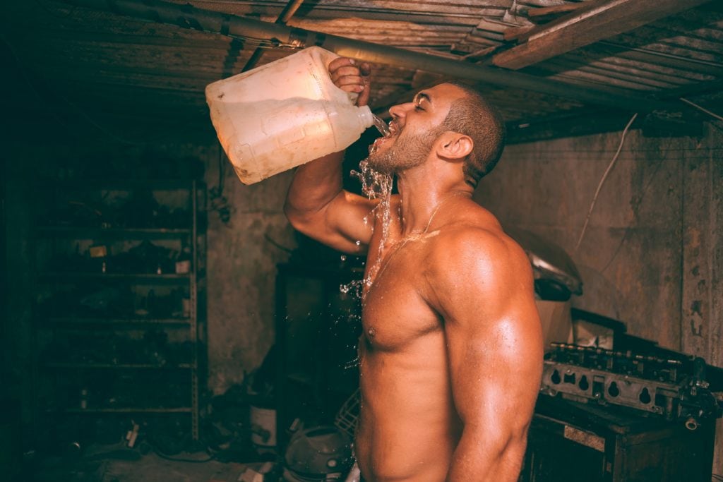 man shirtless chugging water