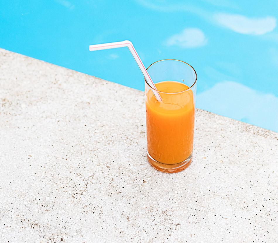 SUPER POWDER orange in a glass with straw by a pool