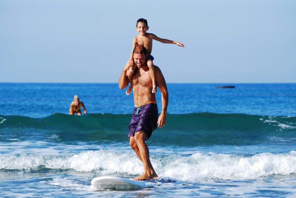 dad with son on shoulders surfing