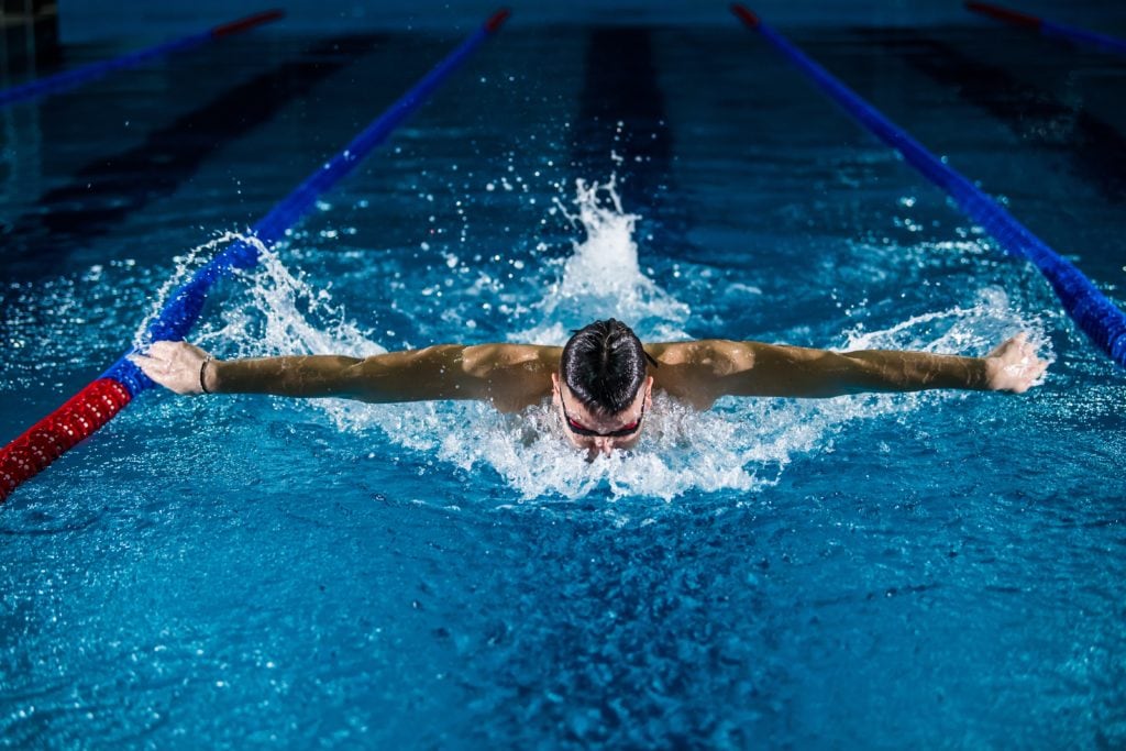 man swimming breast stroke in a pool