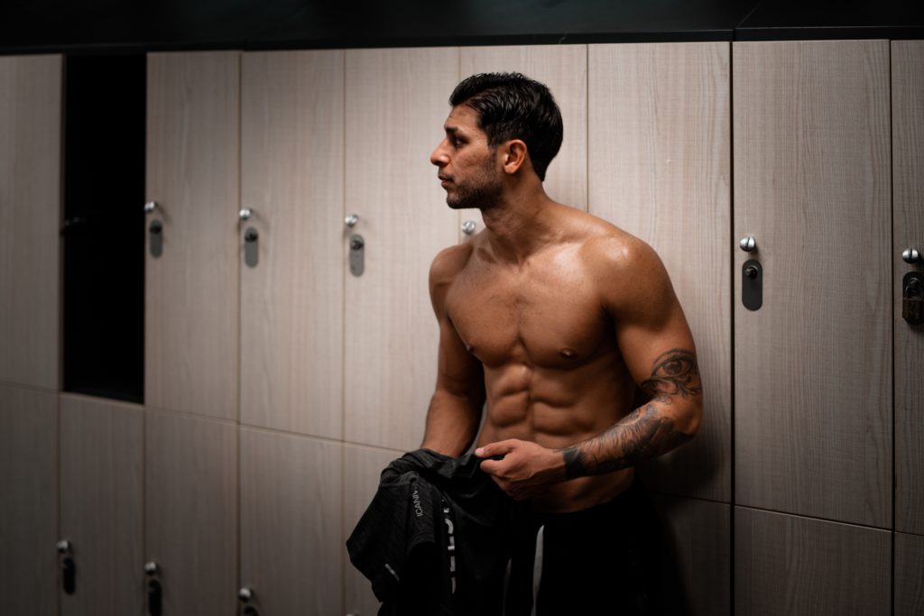 man with shirt off, abs, in locker room