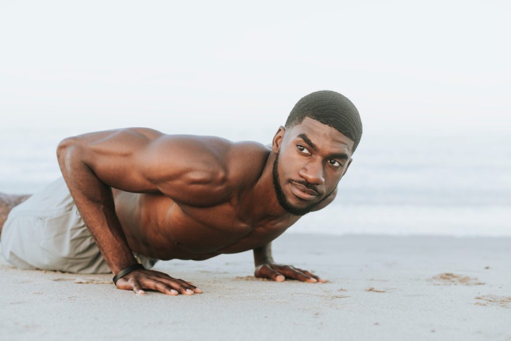 man performing burpees in the sand