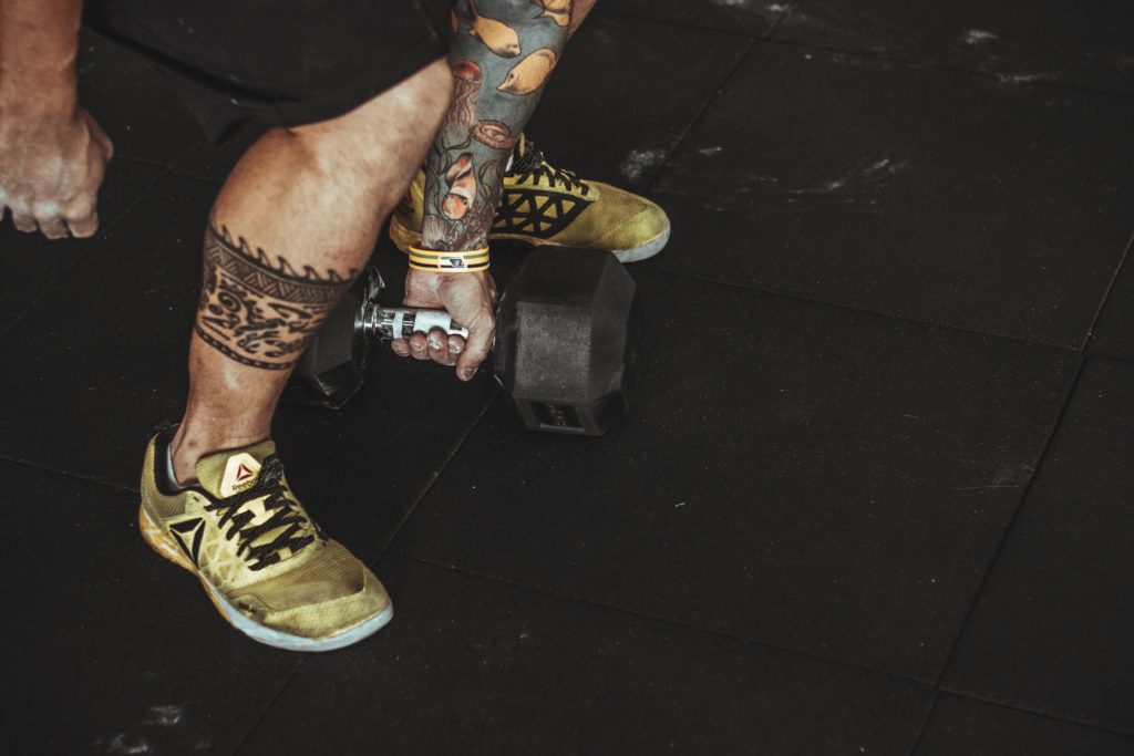 men with tattoos squatting with dumbbell 