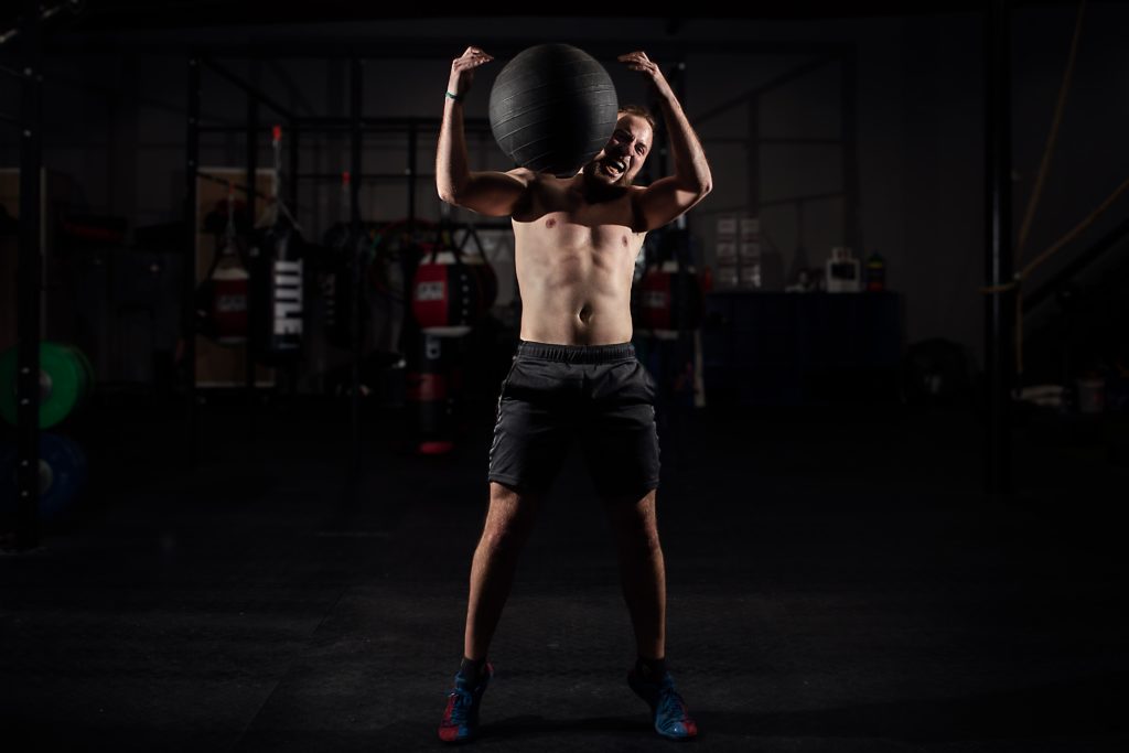 man carrying heavy stability ball on shoulder
