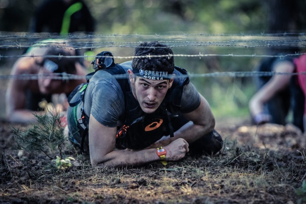spartan race, man crawling under barbed wire