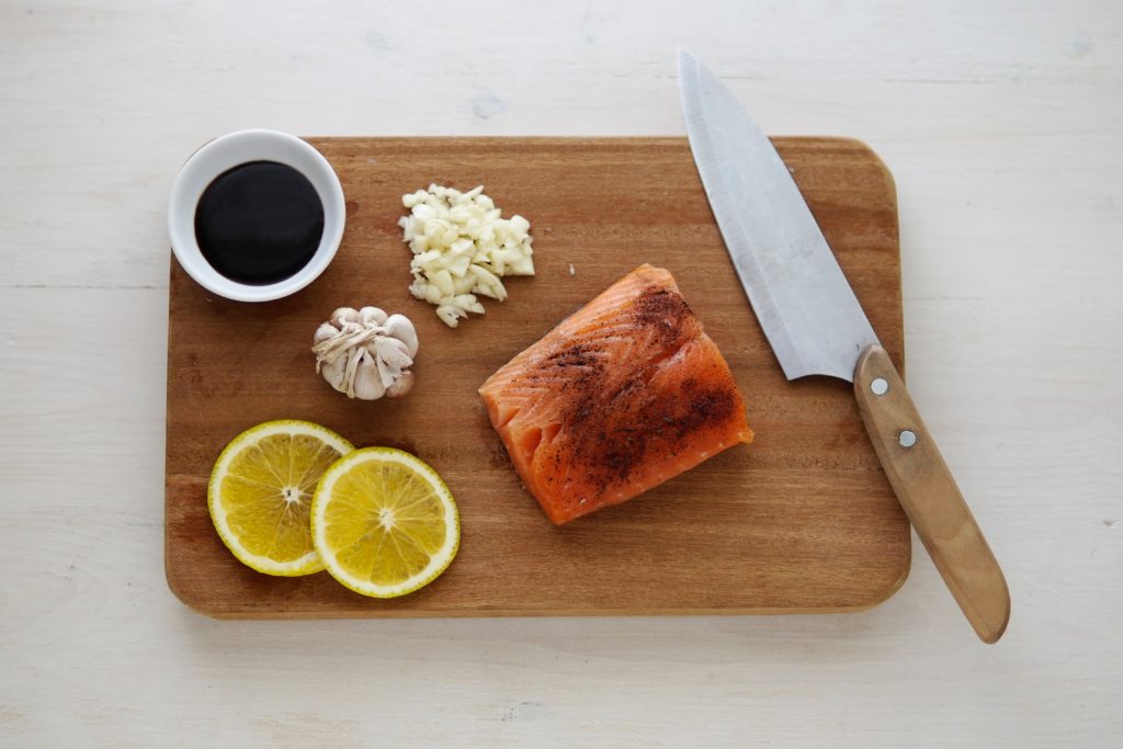 salmon on a cutting board with lemon and garlic