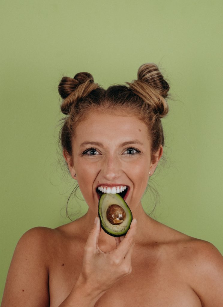 girl biting on an avocado