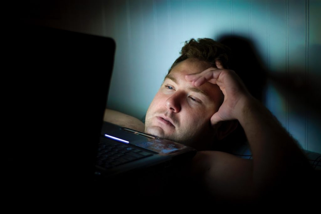 man laying in bed late night working