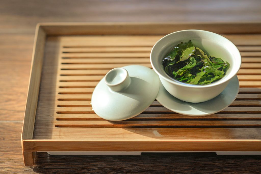 green tea leaves in white bowl on tray for energy