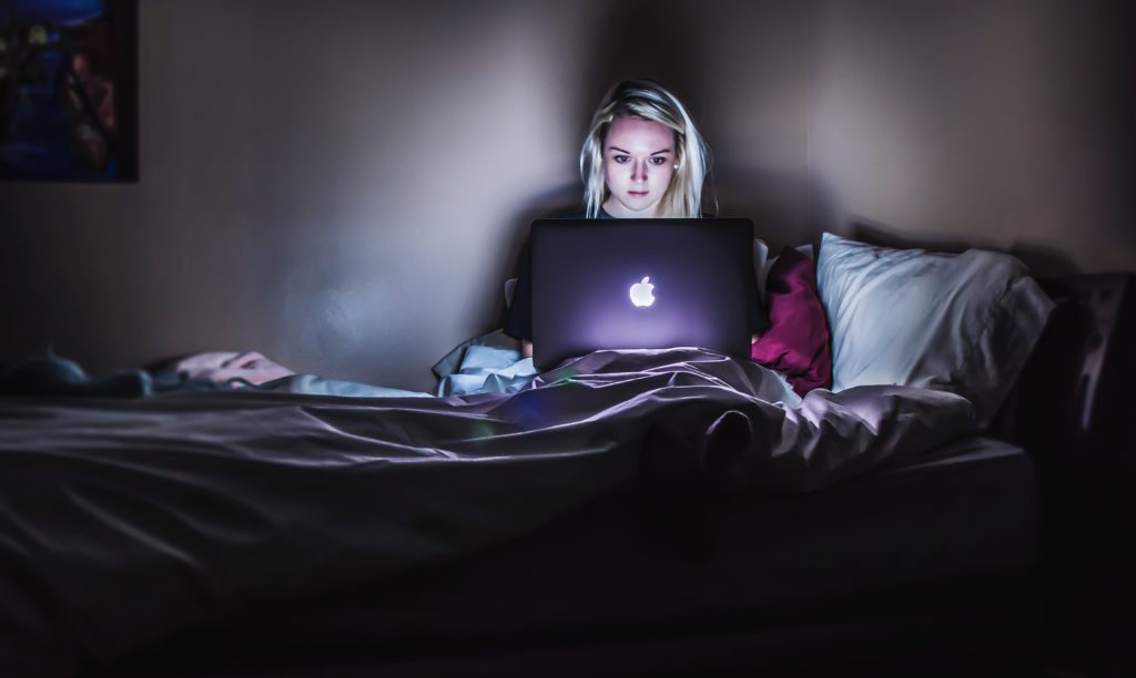 women sitting in bed with laptop